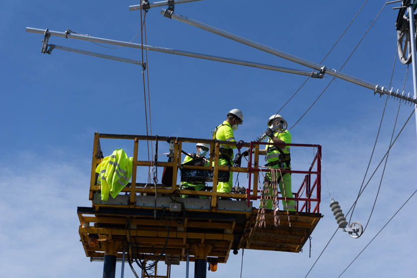 Workers in the elevating work platform of an electrification coach