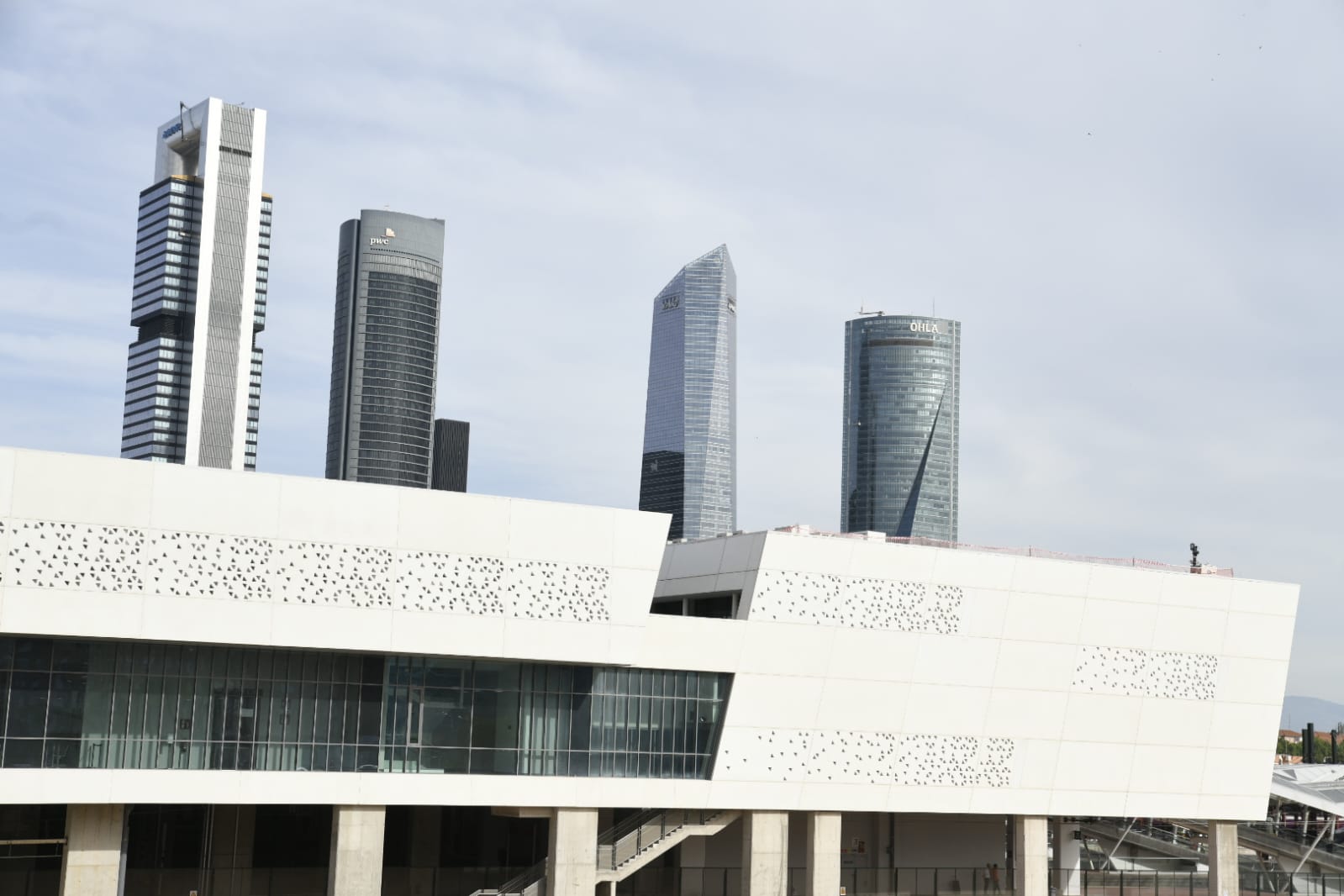 02.06.2026: Vista de la terminal de viajeros de la Estación de Chamartín Clara Campoamor, que muestra la fachada de diseño geométrico y acristalado de la estación con el icónico perfil urbano del área empresarial de las Cuatro Torres al fondo.